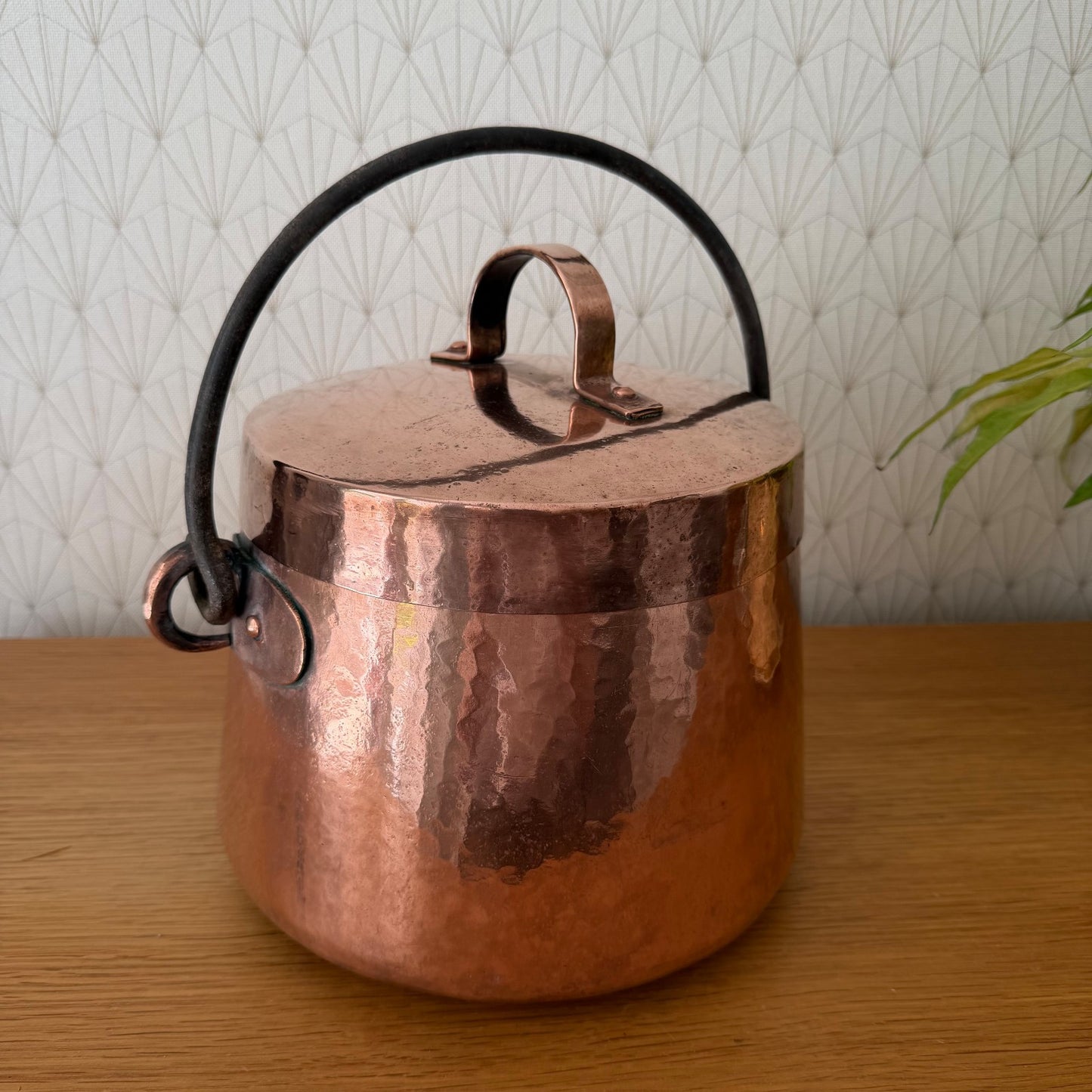 Side view of antique French copper cauldron showing hammered texture and curved handles