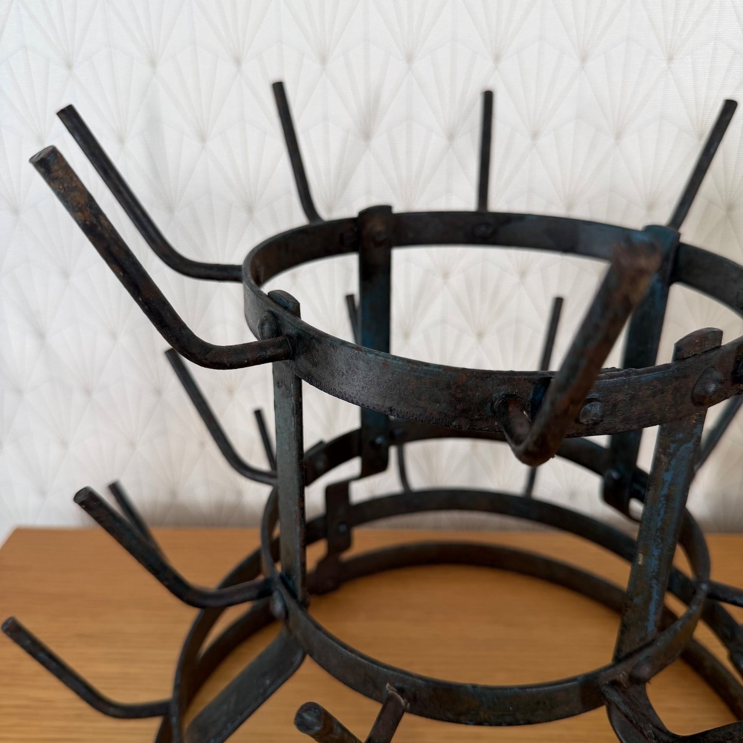 Top-down view of three-tier antique French wrought iron bottle drying rack displaying hook arrangement