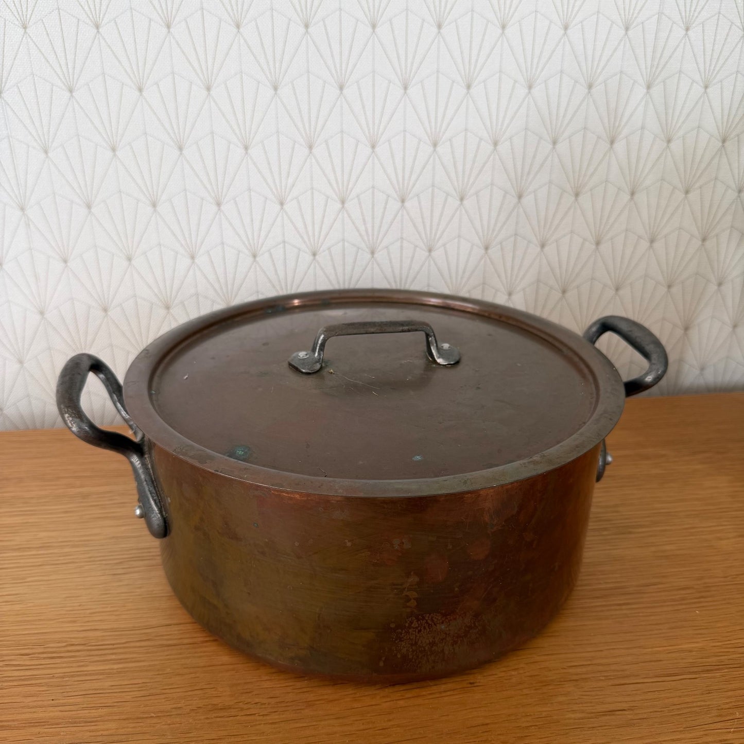 Overhead view of copper cocotte lid with central handle and decorative rim