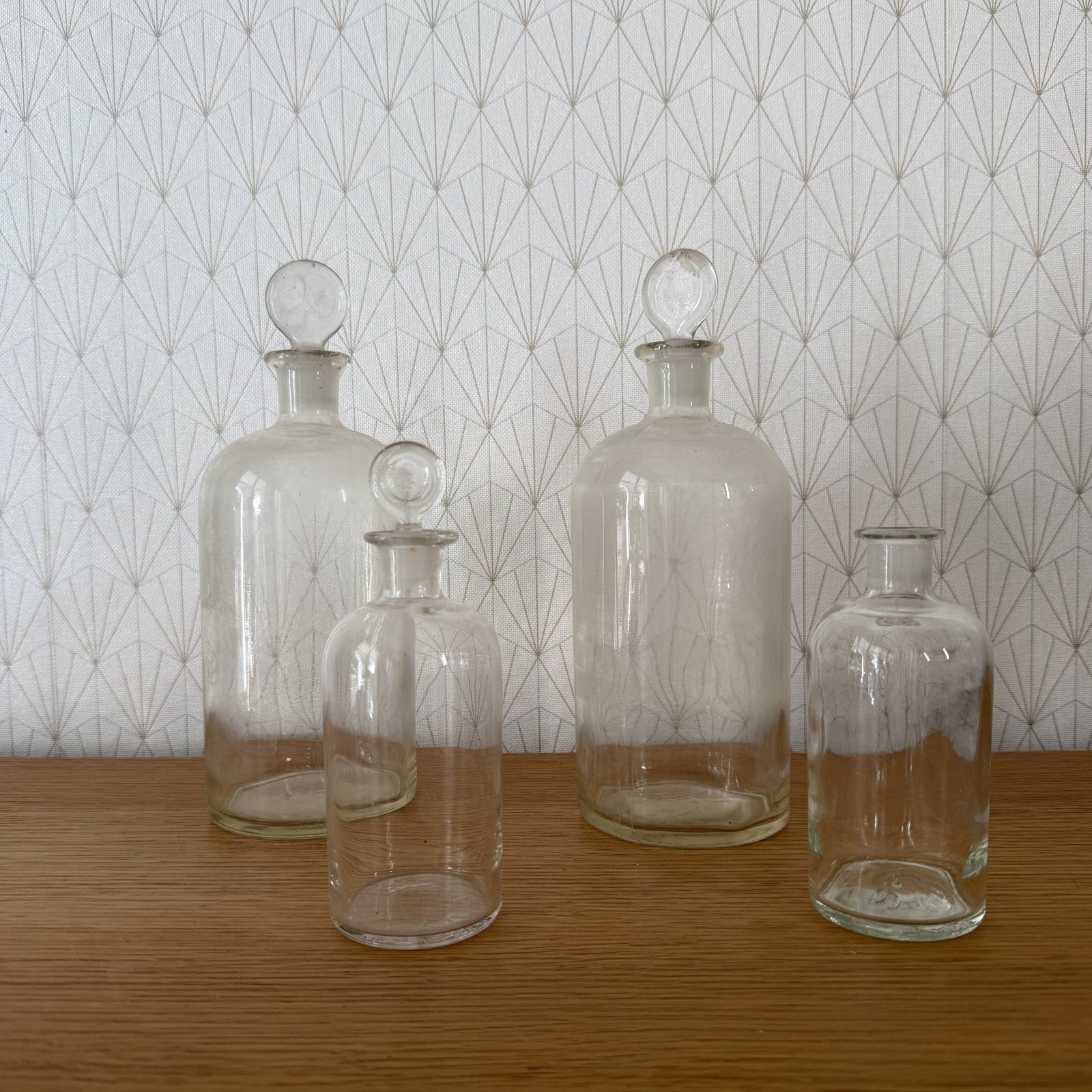 Set of four French apothecary glass bottles with round ball glass stoppers arranged on wooden surface