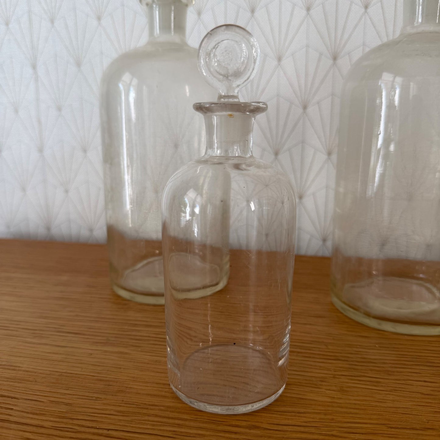 Collection of French pharmacy glass bottles with stoppers shown from side angle