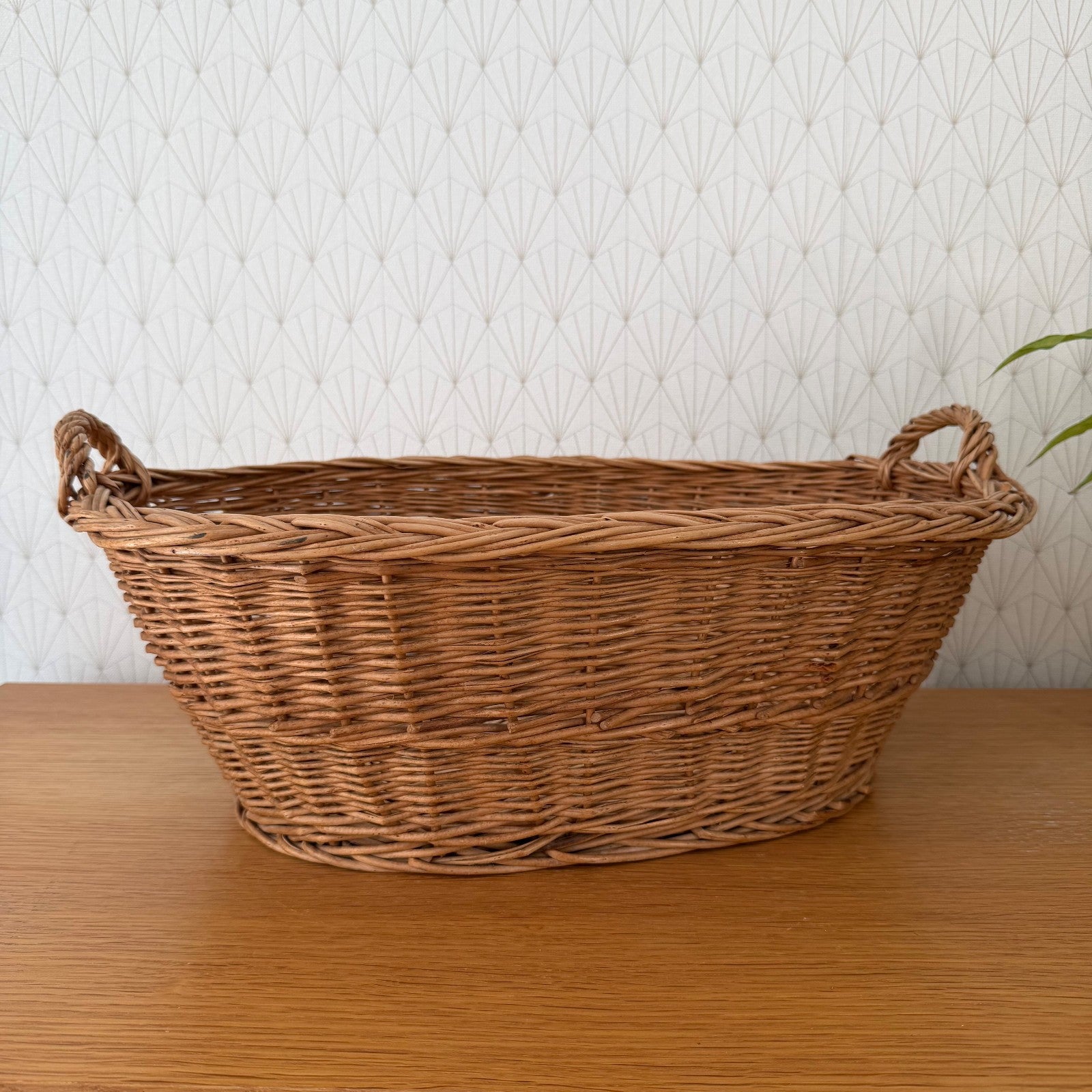 Vintage French wicker laundry basket with twisted handles, oval shape, natural rattan weave