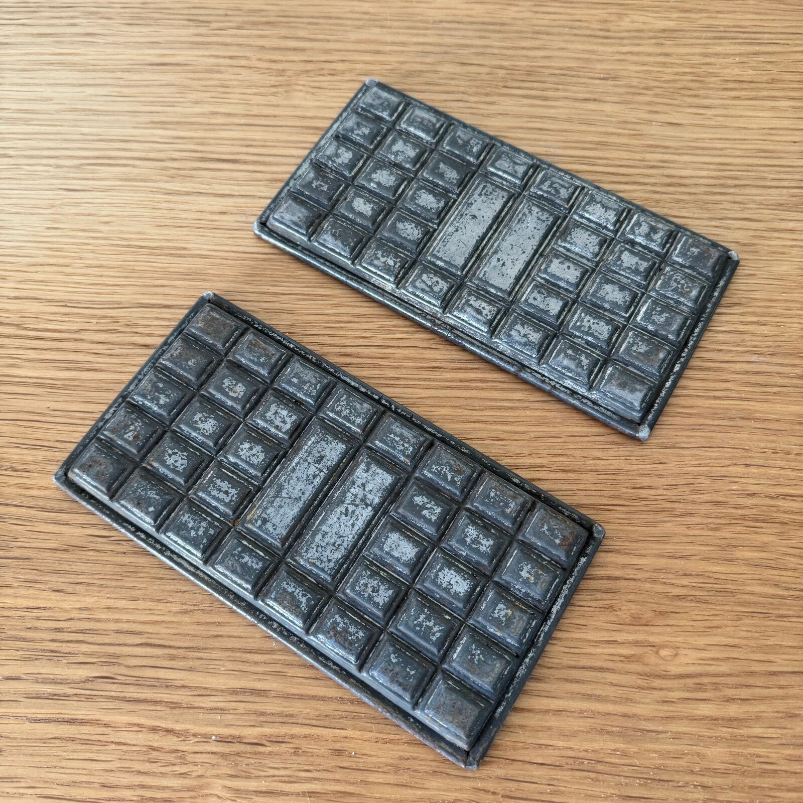 Close-up of French vintage chocolate molds showing grid pattern details and aged metal surface from professional use