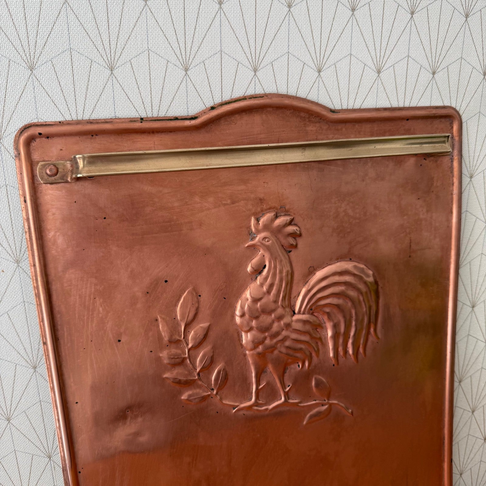 Side profile of vintage copper kitchen hanger showing brass rail and curved base