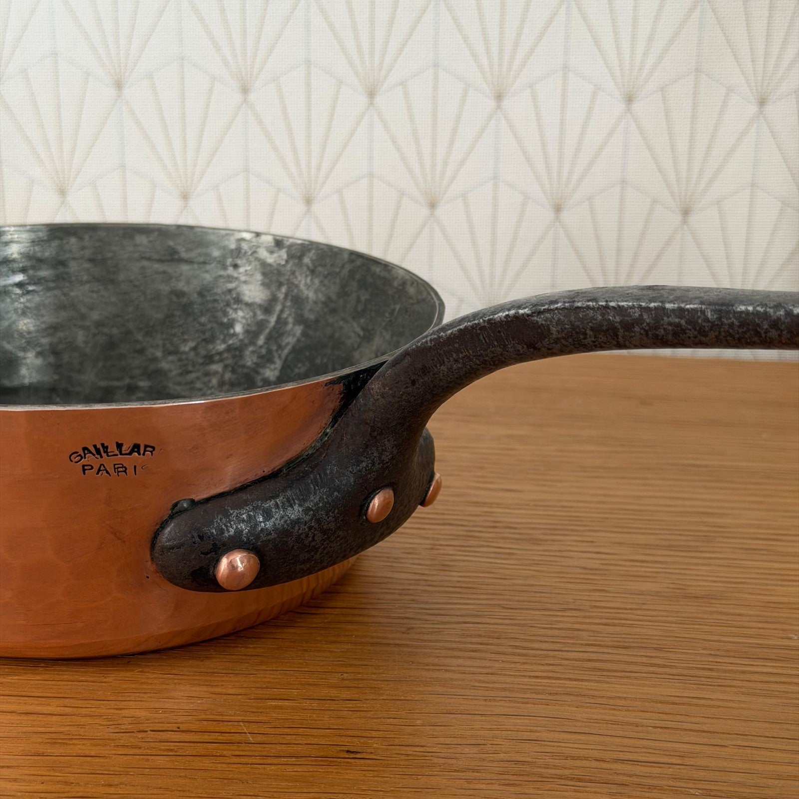 Side profile of hand-hammered French copper sauteuse with copper rivets