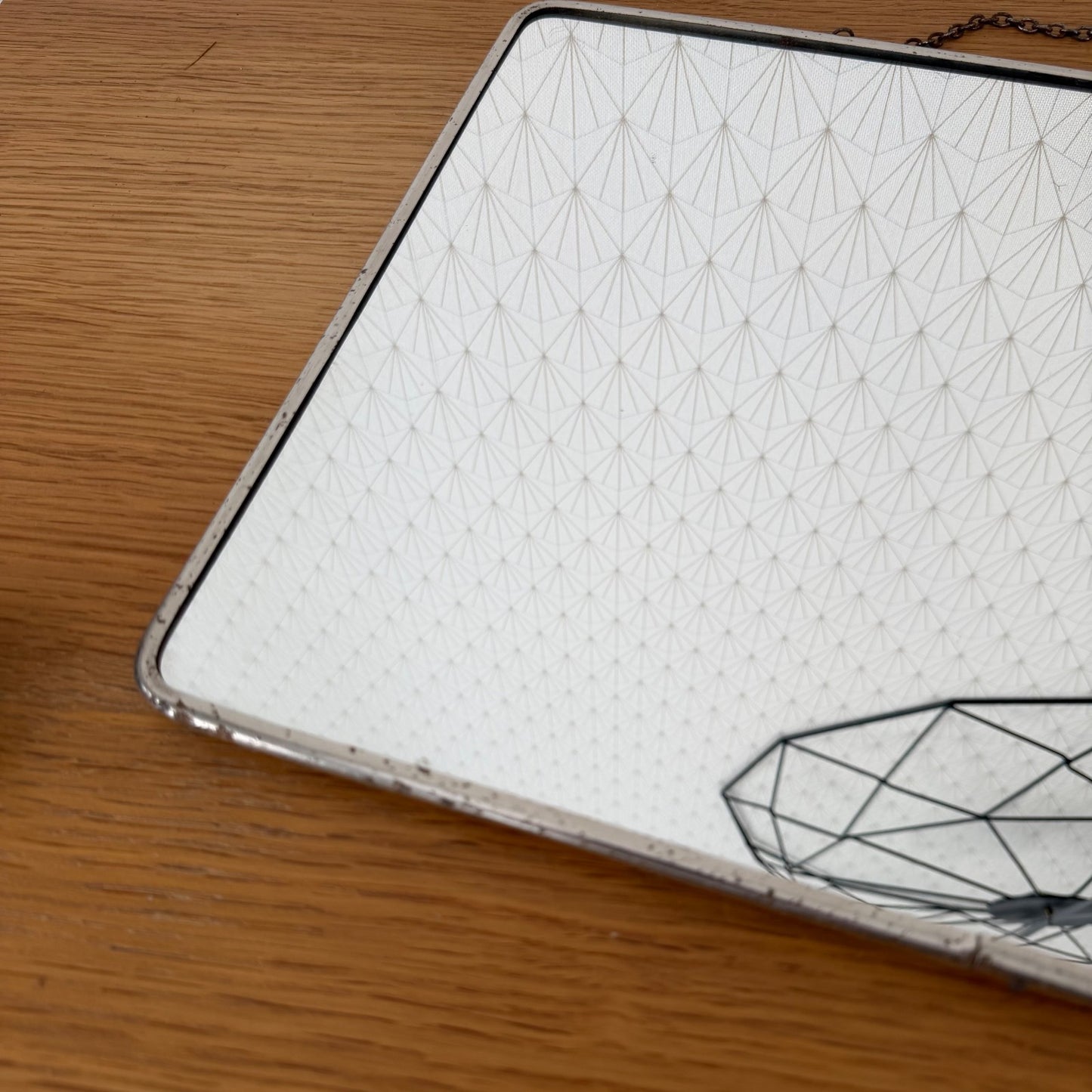 Angled view showing rounded corner and slim metal border of vintage French mirror