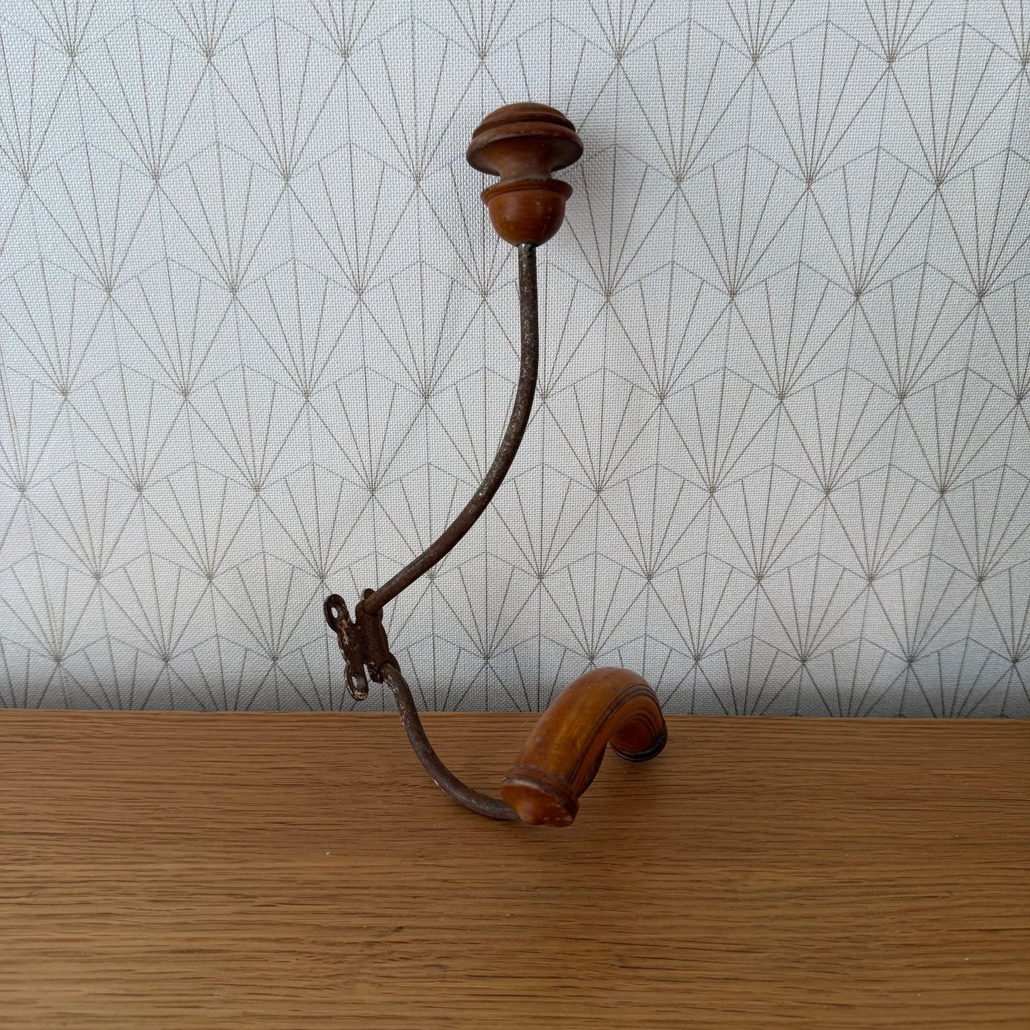 Overhead angle of vintage French wall-mounted coat hook with S-curve iron rod and fruitwood details