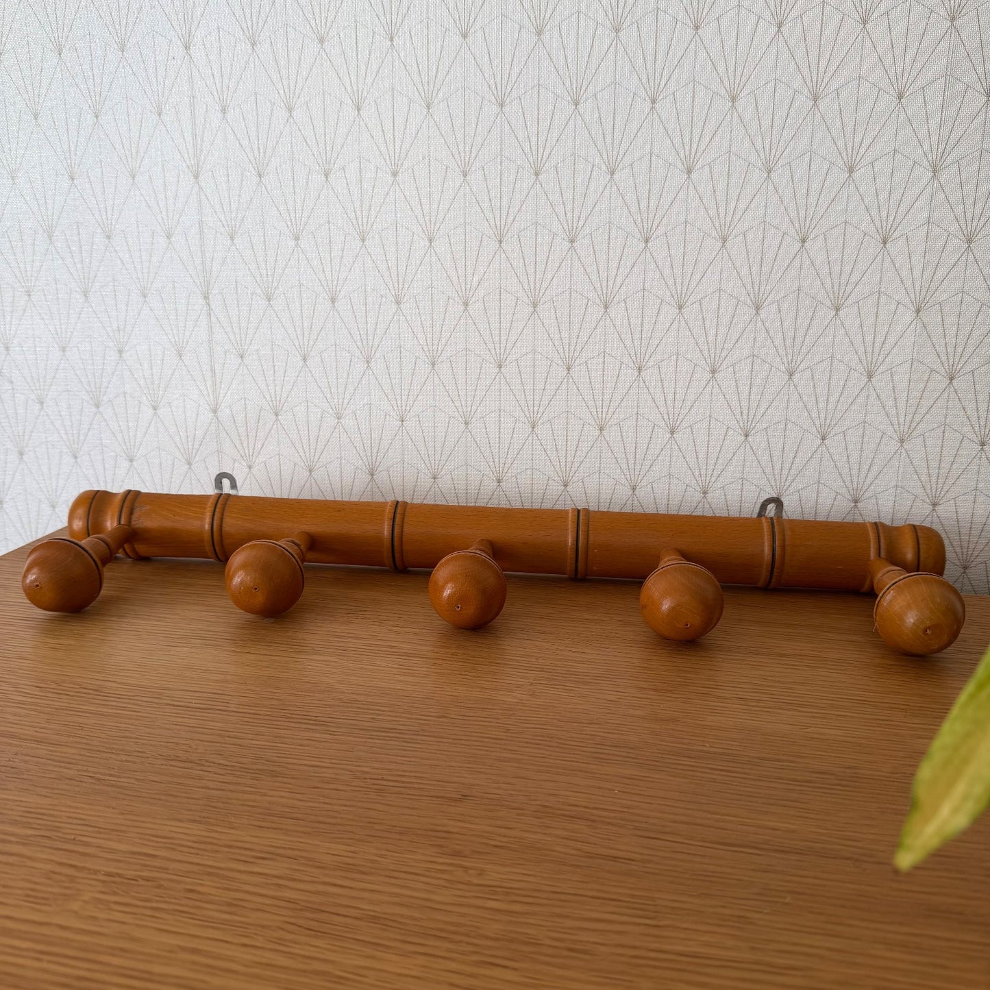 Full length view of French bamboo coat rack mounted on wallpapered wall
