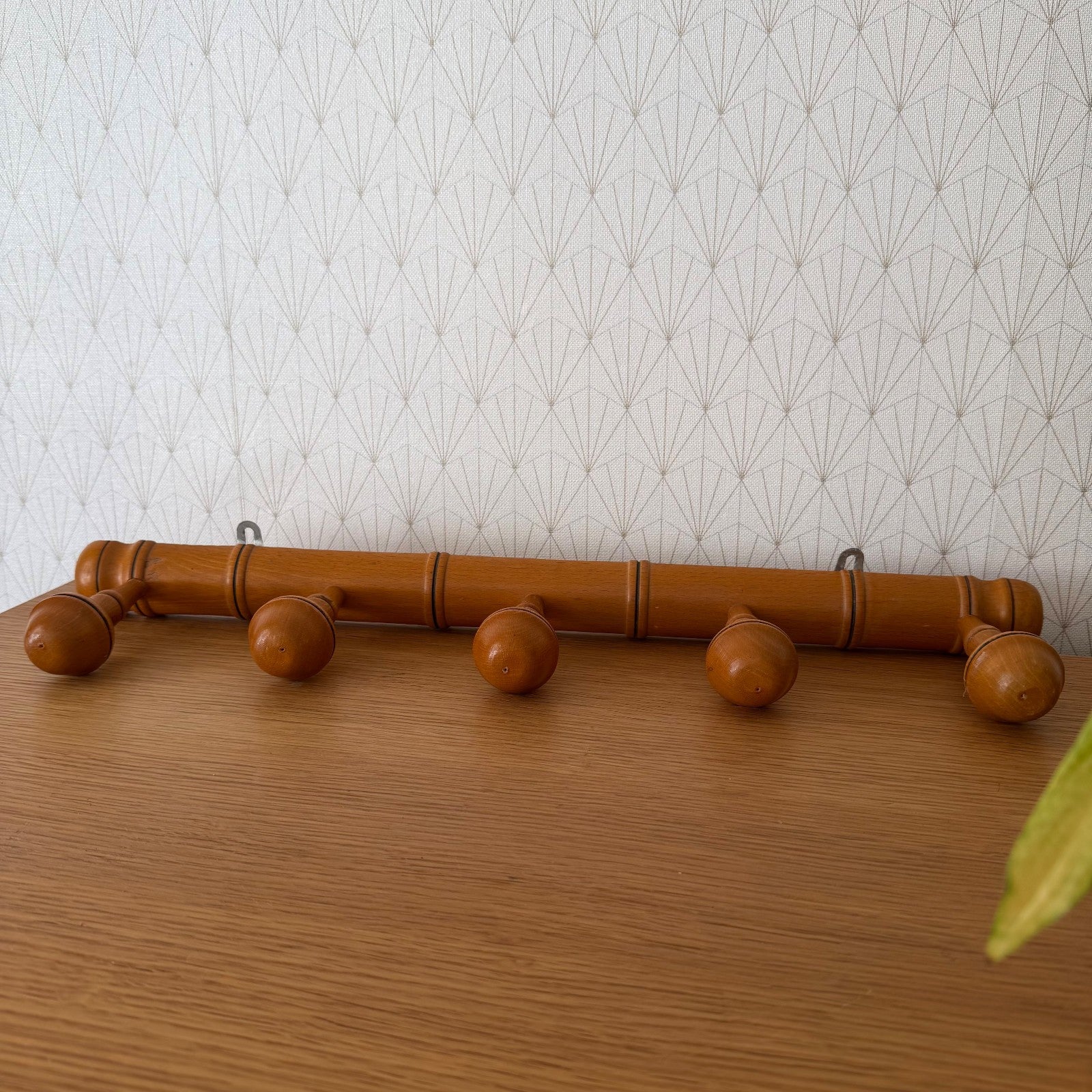Full length view of French bamboo coat rack mounted on wallpapered wall