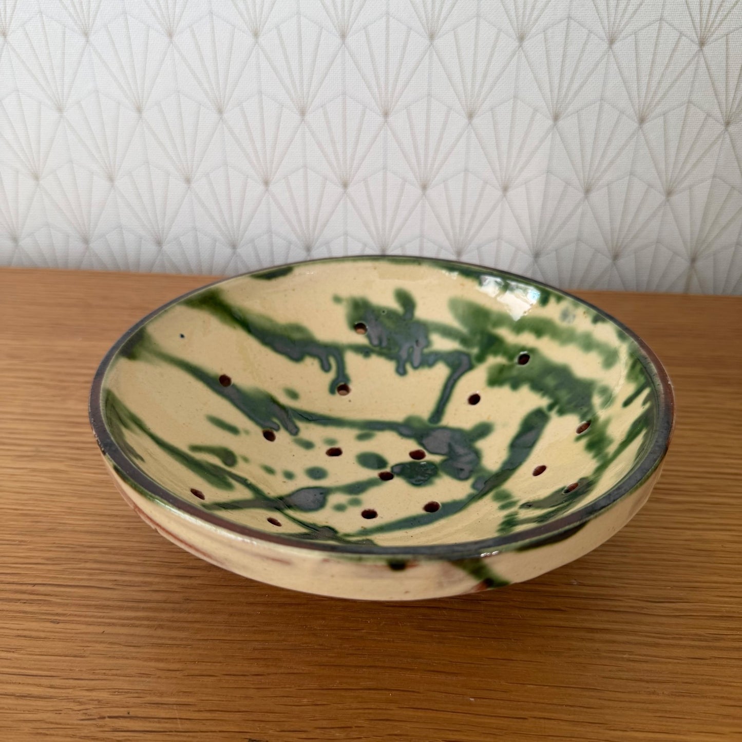 Rustic French pottery perforated colander with cream slip and terracotta glaze, detail view