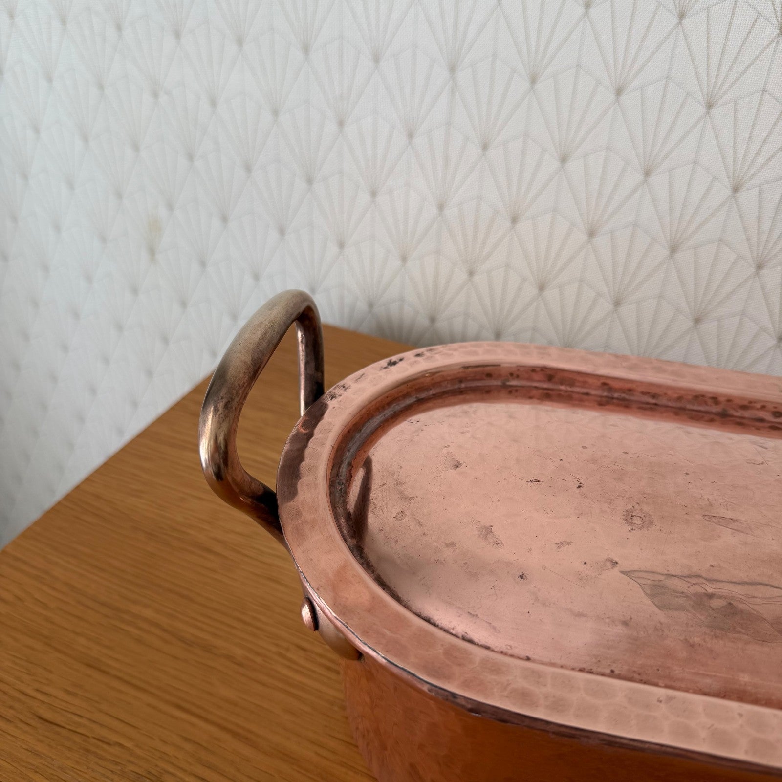 Side profile of elongated French copper fish kettle on wooden display table