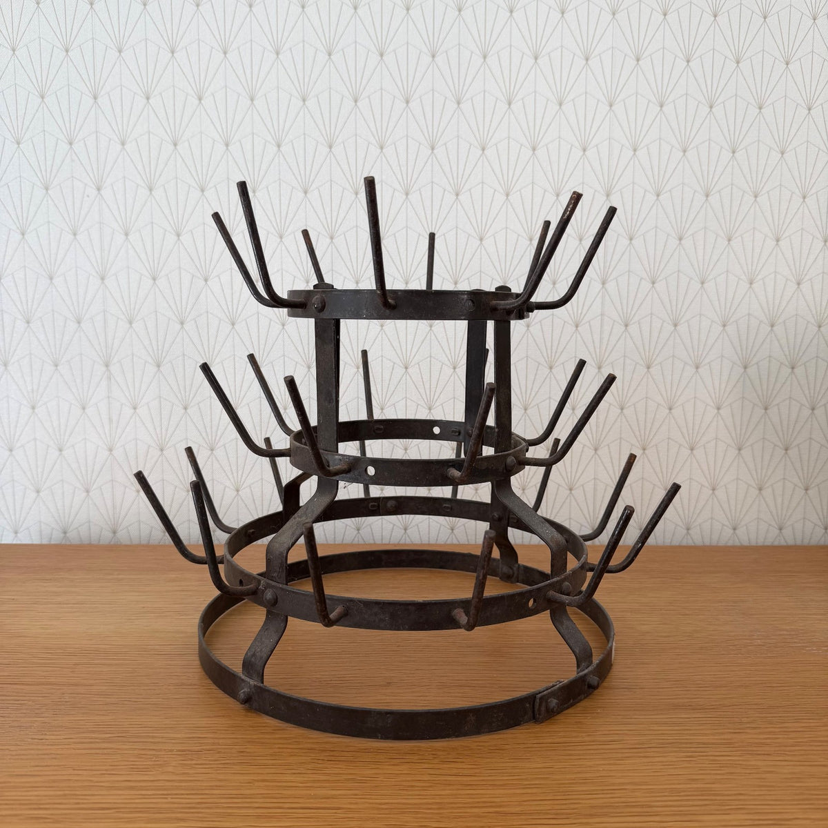 Antique French wrought iron bottle drying rack with three tiered circular rings and forked prongs, full view
