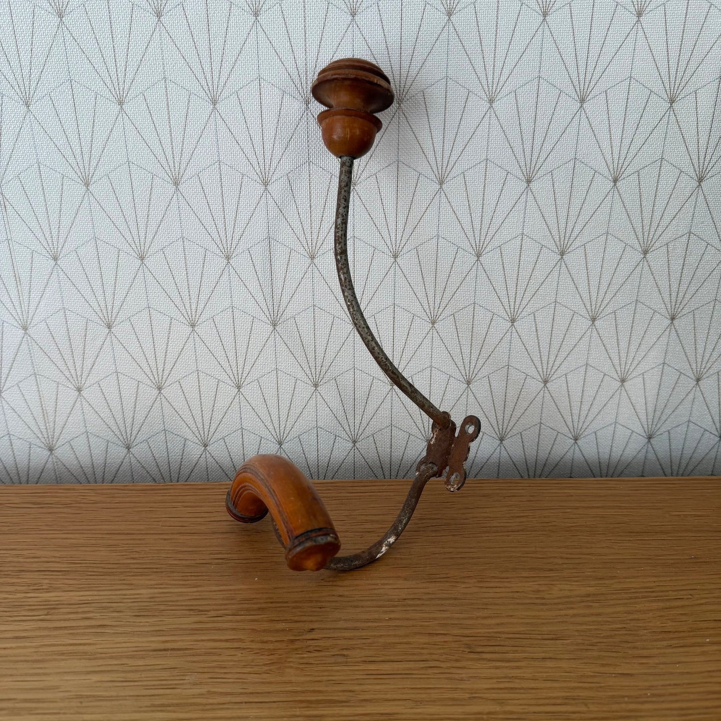 Side view of 1950s French coat hook showing curved wooden rest and forged iron swing arm mechanism