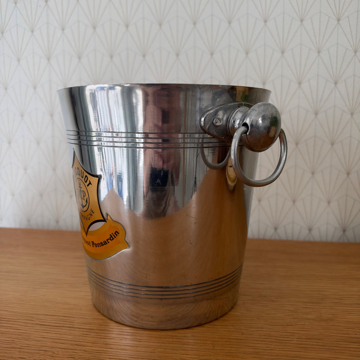 Side profile of vintage Veuve Clicquot bucket with metal ring handles and decorative label