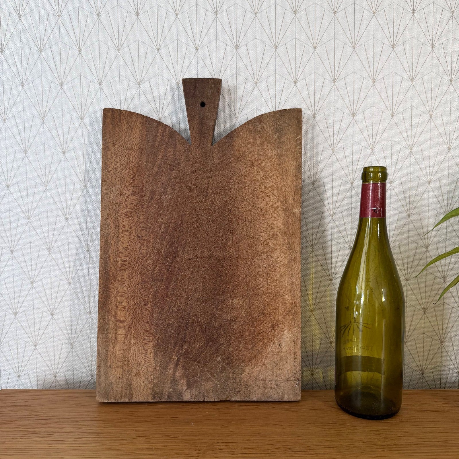 Close-up detail of carved wooden handle and lobed top edge of antique French bread board