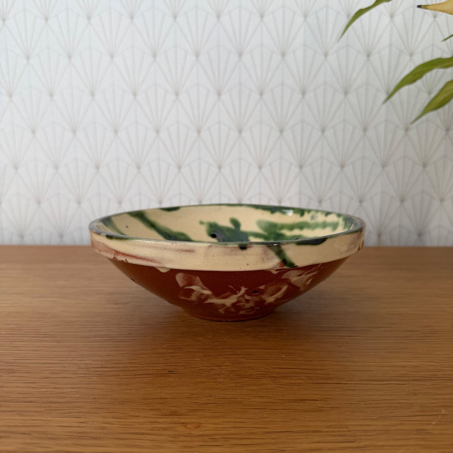 Vintage French pottery fruit colander bowl with cream interior and terracotta exterior, side view