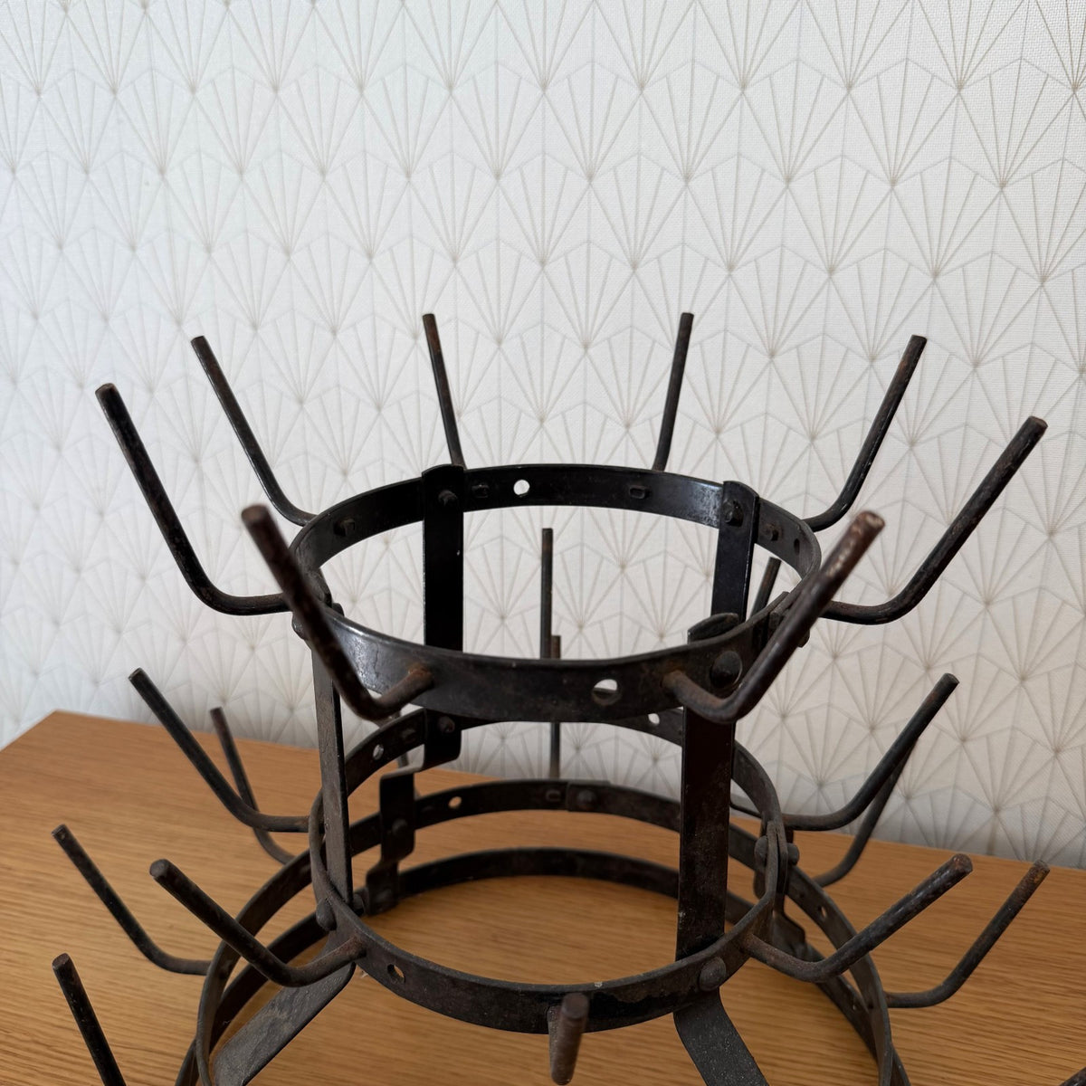 Close-up detail of three-tier French iron bottle rack showing hand-riveted construction and forked hooks