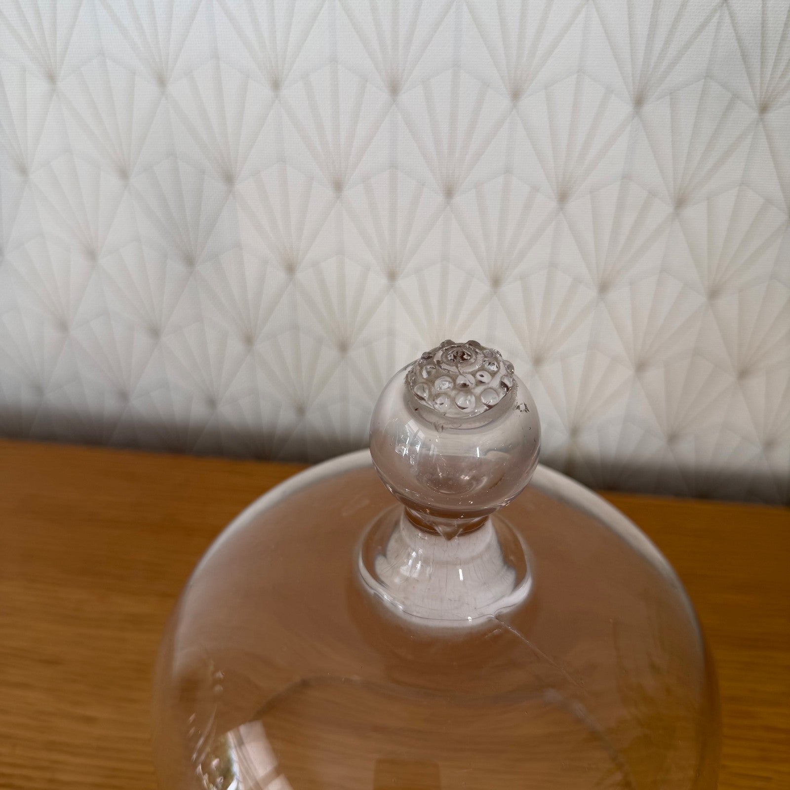 Vintage French glass cloche dome bell jar seated on wood surface with decorative background