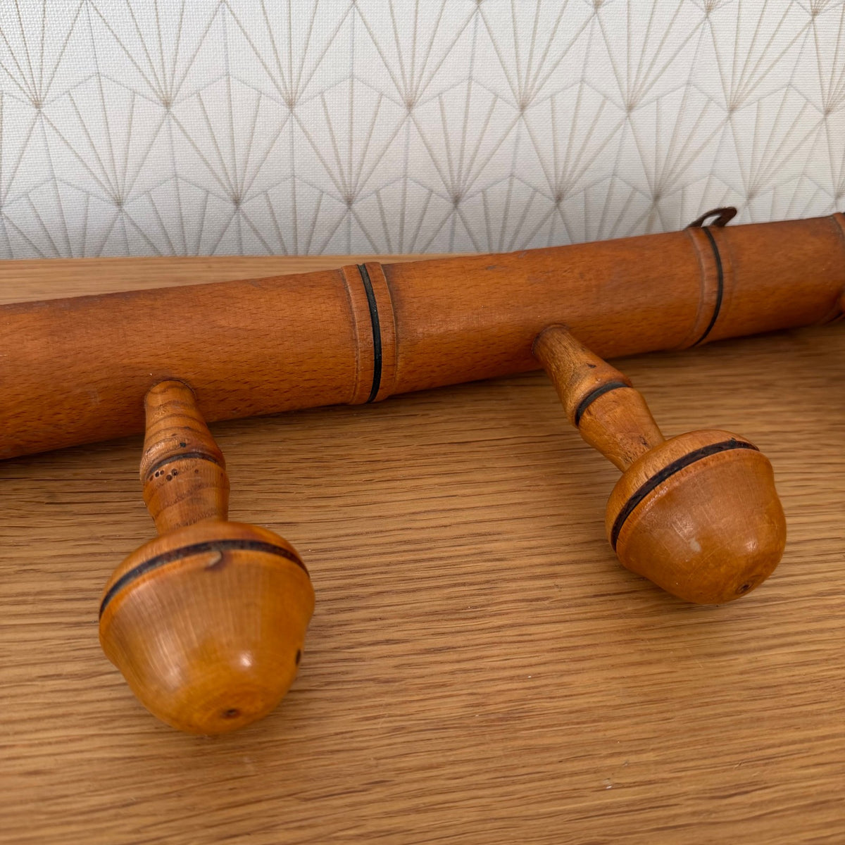 Side profile of antique French wood coat rack showing cylindrical rail and peg construction