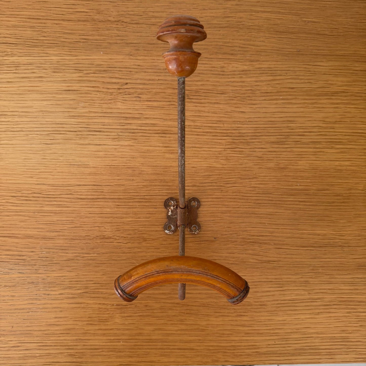 French vintage coat hook wall mount with turned wooden finial and metal bracket on wooden background