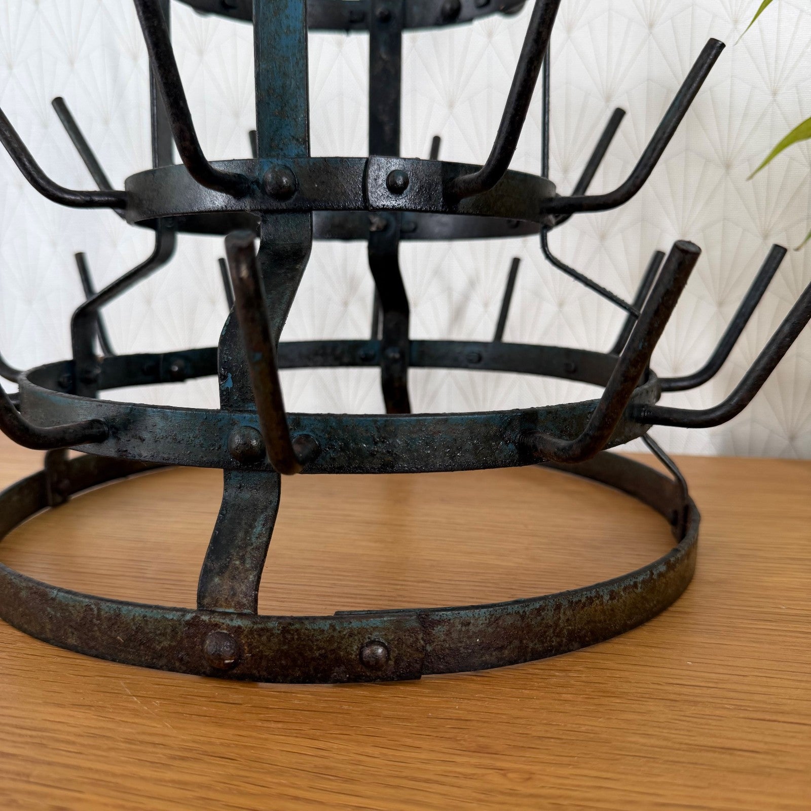 Side angle detail of antique French bottle rack tiers with curved iron hooks and patina