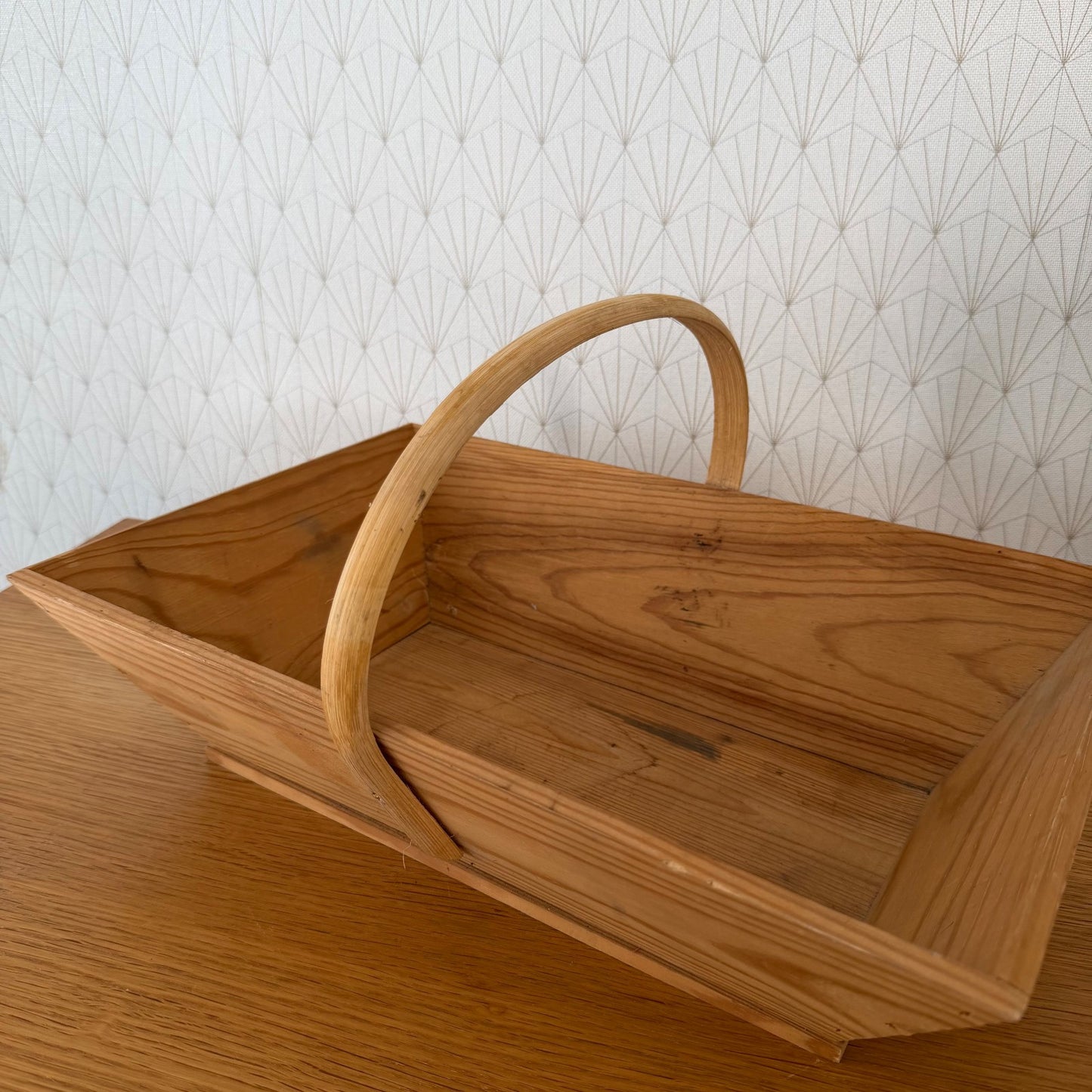 Angled view of traditional French wooden harvest basket with bentwood handle