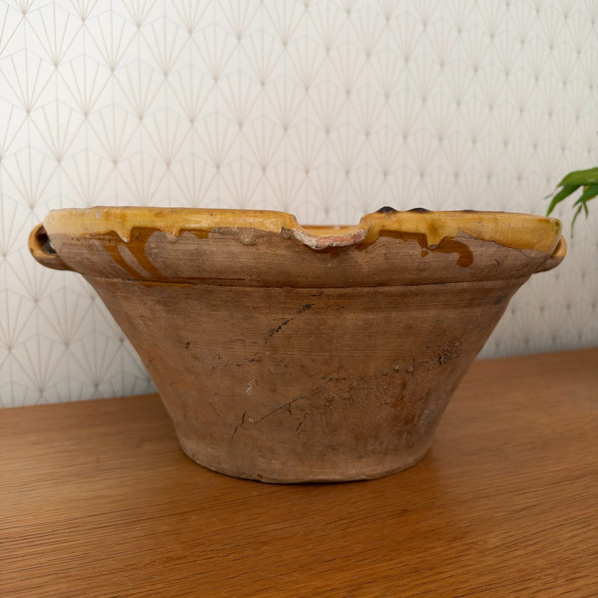 Back view of antique French terracotta tian bowl showing unglazed exterior with surface weathering, rim chips, glaze drips, and small chip at rim edge.
