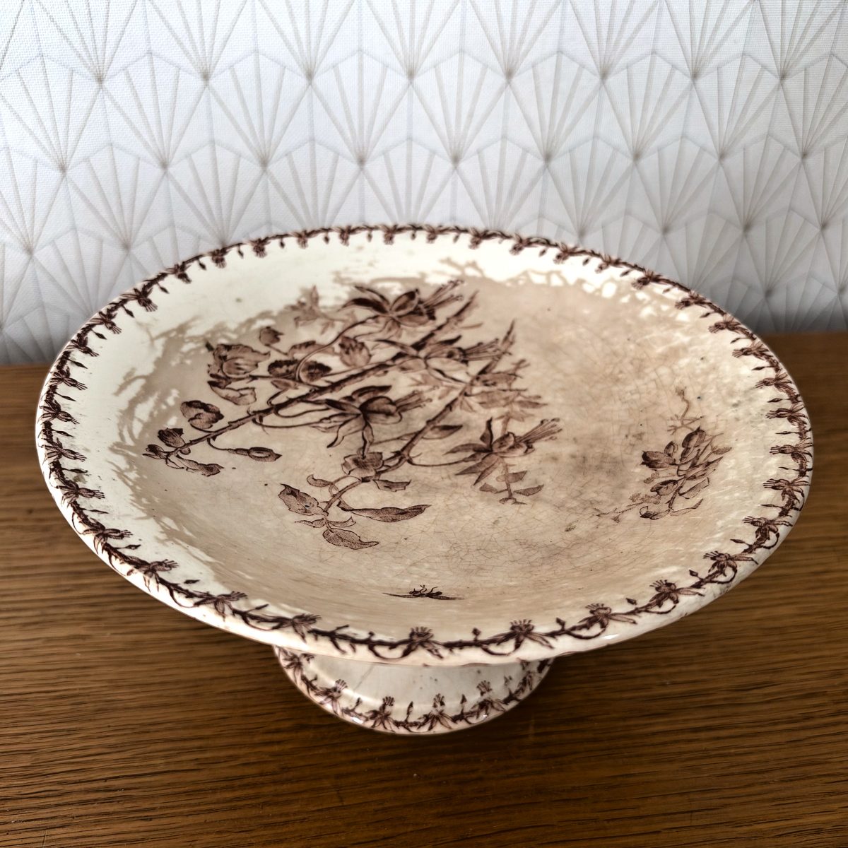 Top-down view of Gien ironstone tazza showing central brown floral spray and decorative vine border around the rim.