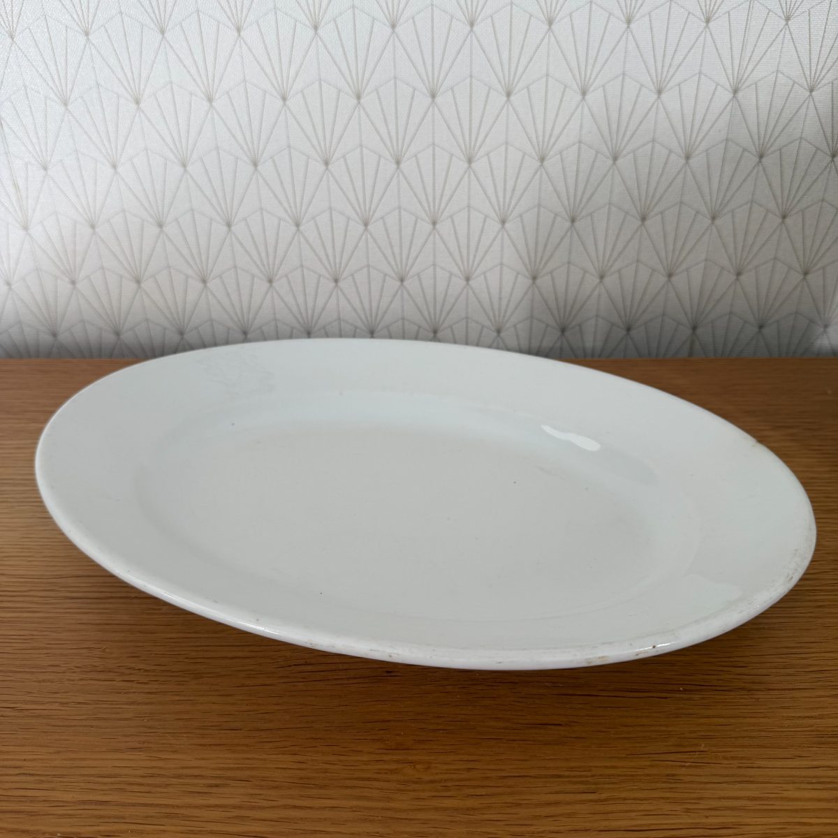 Top-angle view of antique French white ironstone oval platter showing smooth glazed interior and wide flat rim.