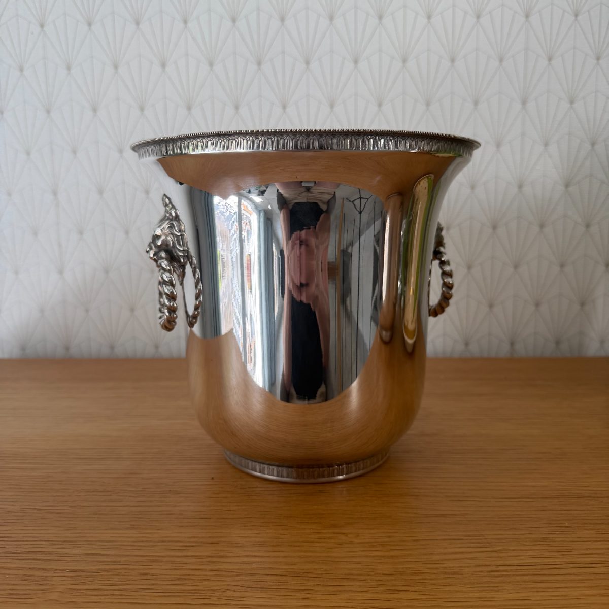 Vintage French silver plated champagne ice bucket with lion head ring handles, front view, highly polished finish, flared rim with beaded and arch border detail.