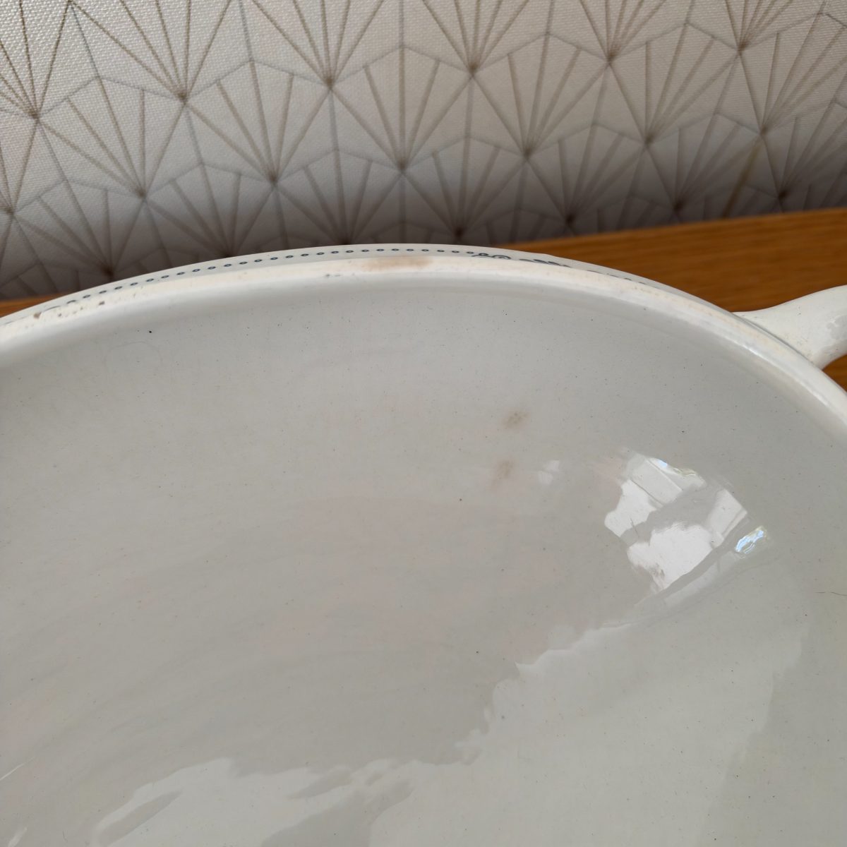 Close-up of antique French ironstone tureen base interior showing light brown age staining and fine crazing in the white glaze.