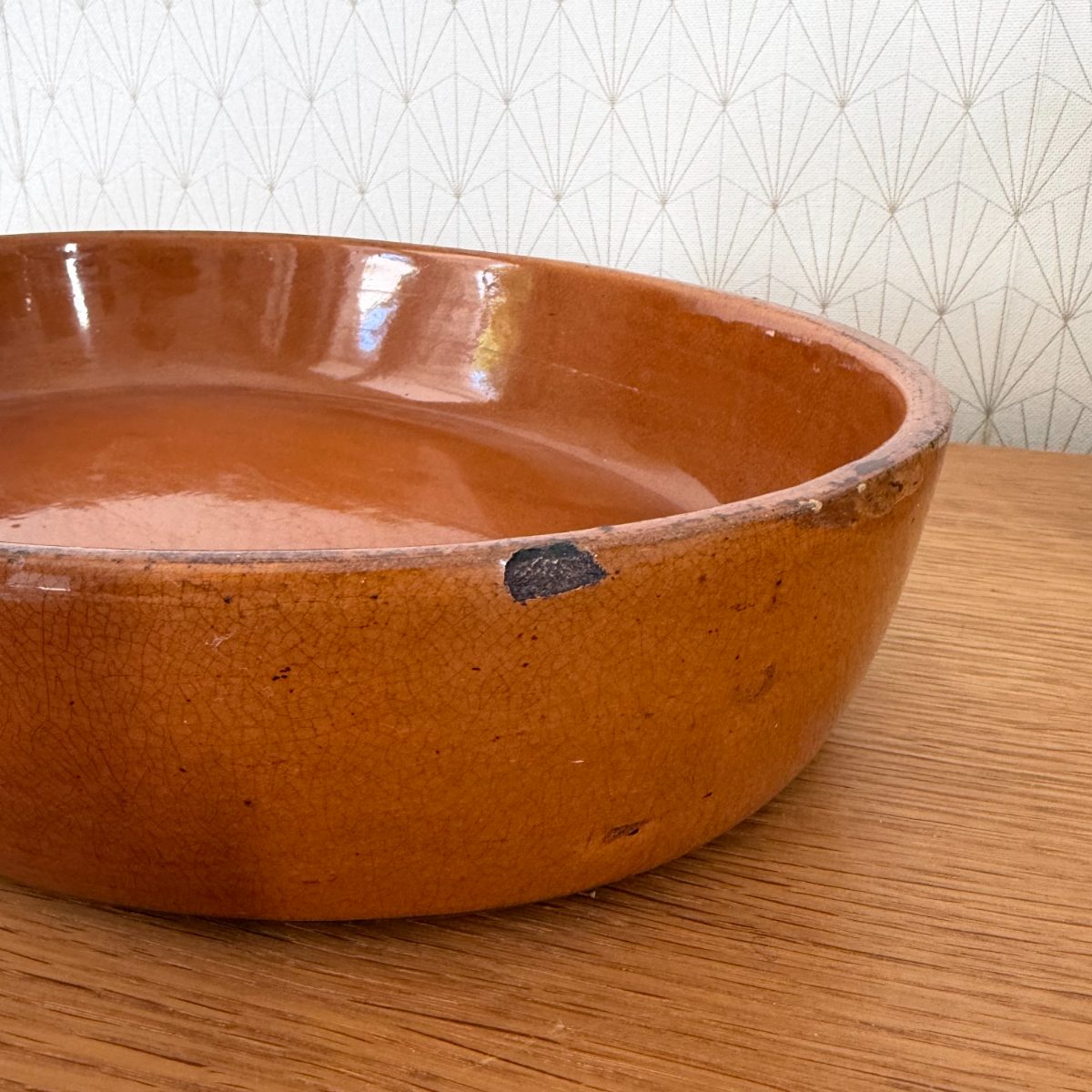 Close-up of French terracotta dish rim showing crazing, small glaze losses and aged patina on the amber-glazed exterior.