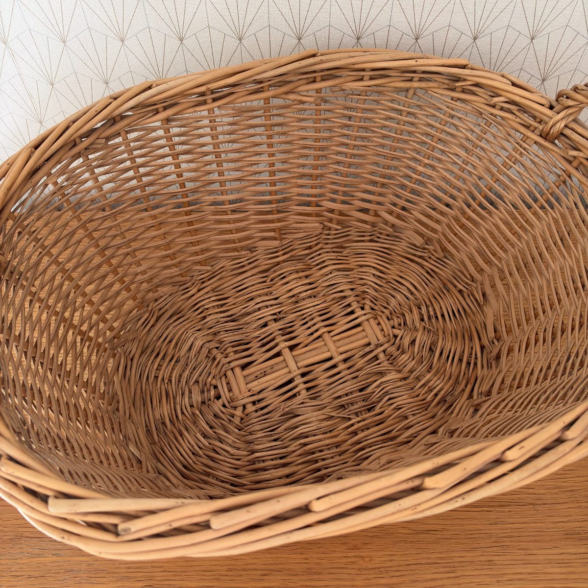 Close-up interior view of vintage French wicker laundry basket showing hand-woven rattan construction and oval base weave pattern.