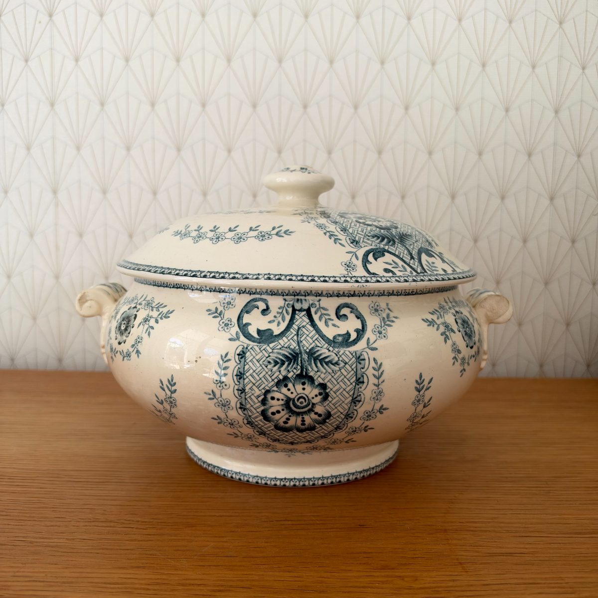 Antique French blue white transferware faience soup tureen with lid, front view, floral and scrollwork motifs on cream earthenware, on oak surface.