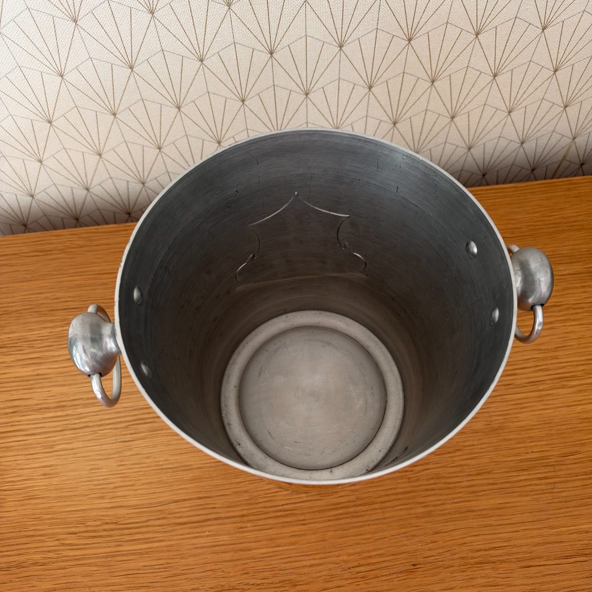 Top down interior view of Veuve Clicquot aluminium champagne ice bucket showing embossed crest on inner wall and circular base.