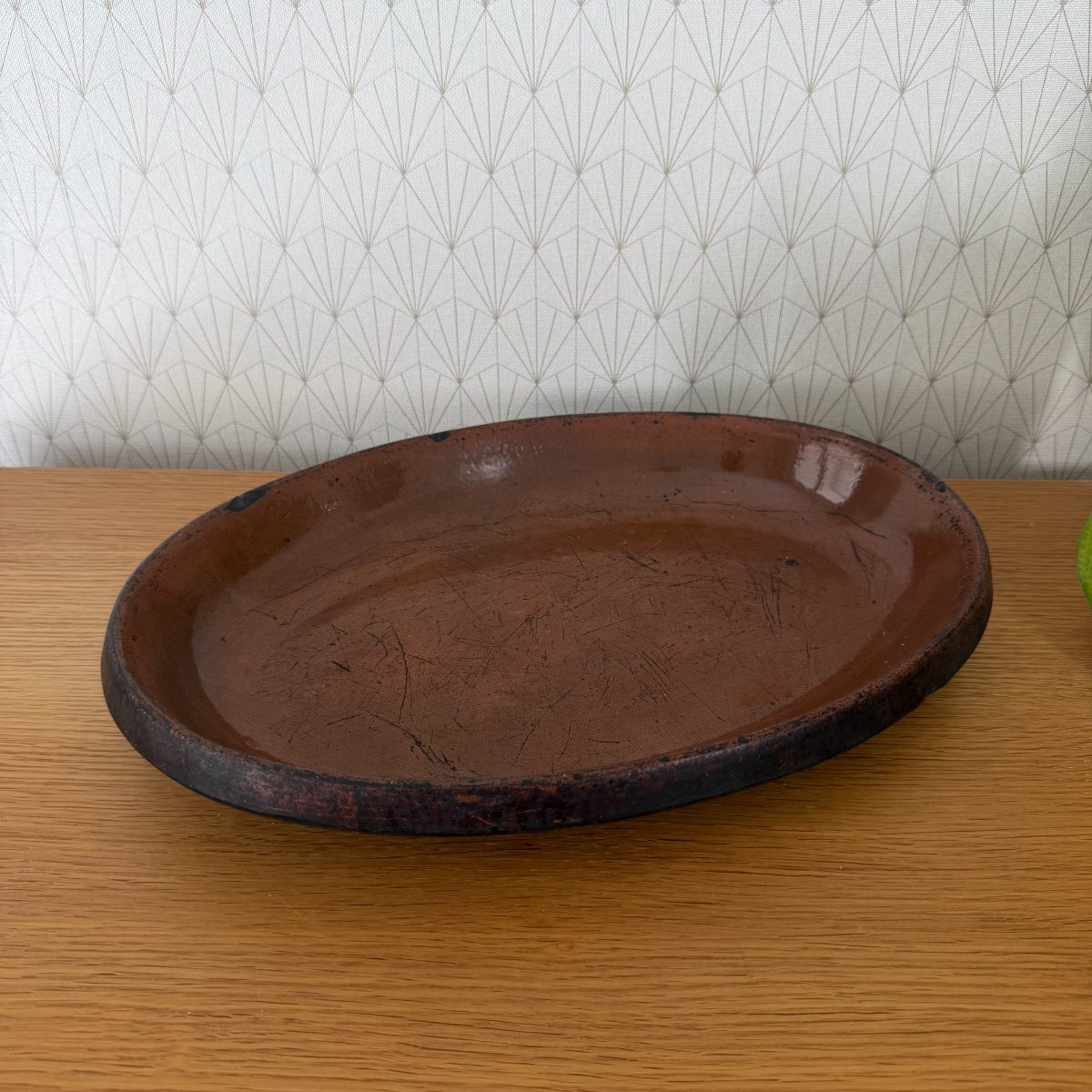 Three-quarter top view of a vintage French oval terracotta dish showing brown glaze and use marks across the interior surface.
