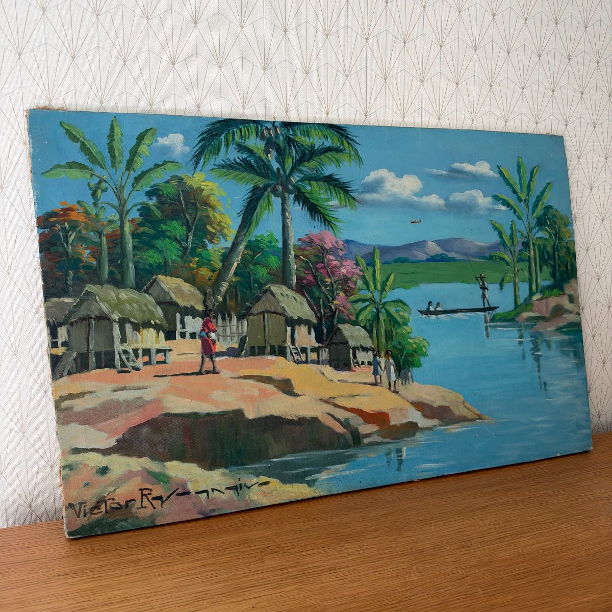 Side view of vintage signed oil painting on canvas showing tropical village in Senegal with palm trees, thatched huts, river and boat with figures