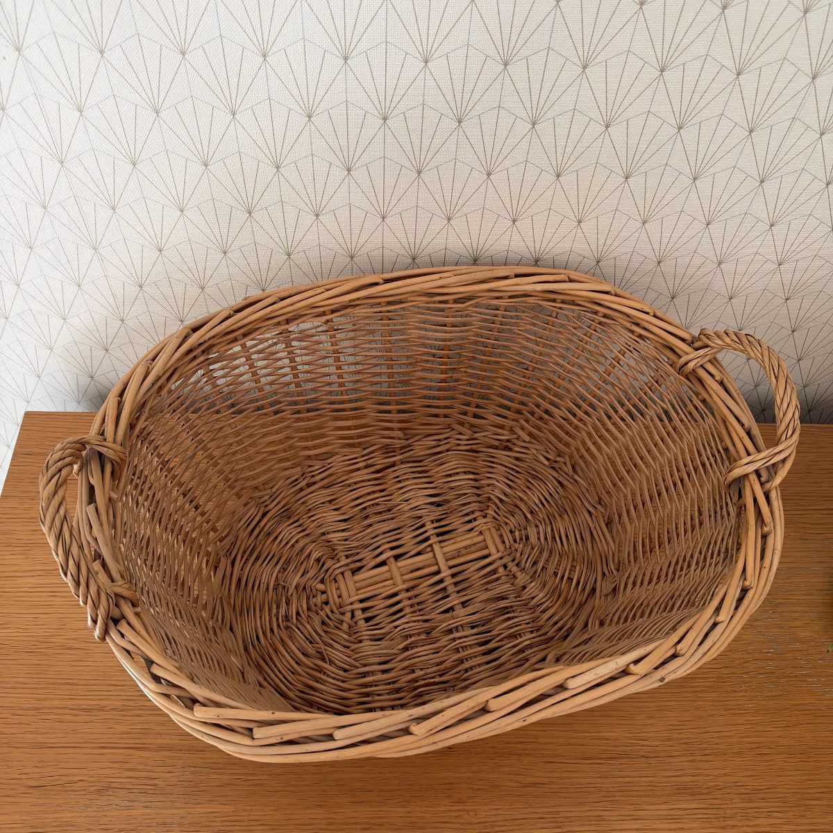 Top-down view of vintage French wicker laundry basket showing spiral woven base and open oval interior.