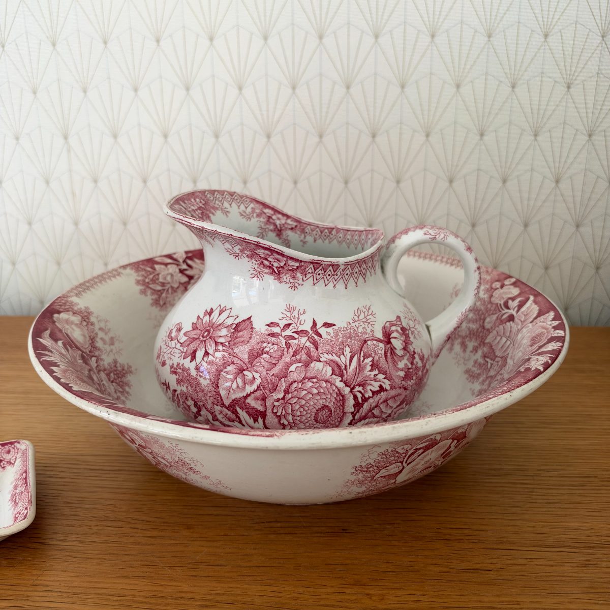 Front view of red transferware ironstone pitcher seated inside large matching wash basin, dense floral botanical transfer print in cranberry pink.