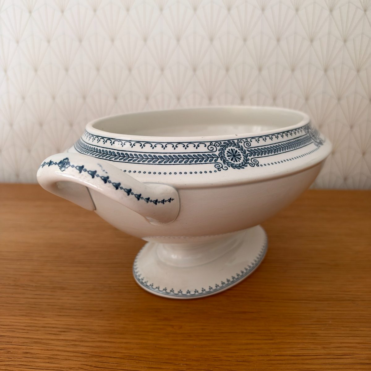 Opposite side view of antique French ironstone tureen base showing handle chip detail, blue transferware decoration, and oval pedestal foot.