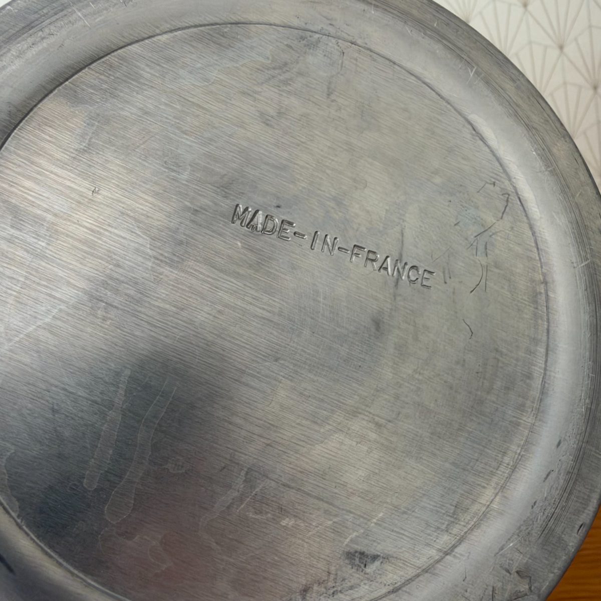 Bottom of vintage French aluminium champagne ice bucket stamped MADE-IN-FRANCE with wear and scratches visible.