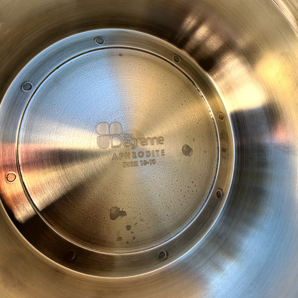Underside of Guy Degrenne Aphrodite punch bowl showing the engraved logo, Aphrodite name, and Inox 18-10 stainless steel mark.