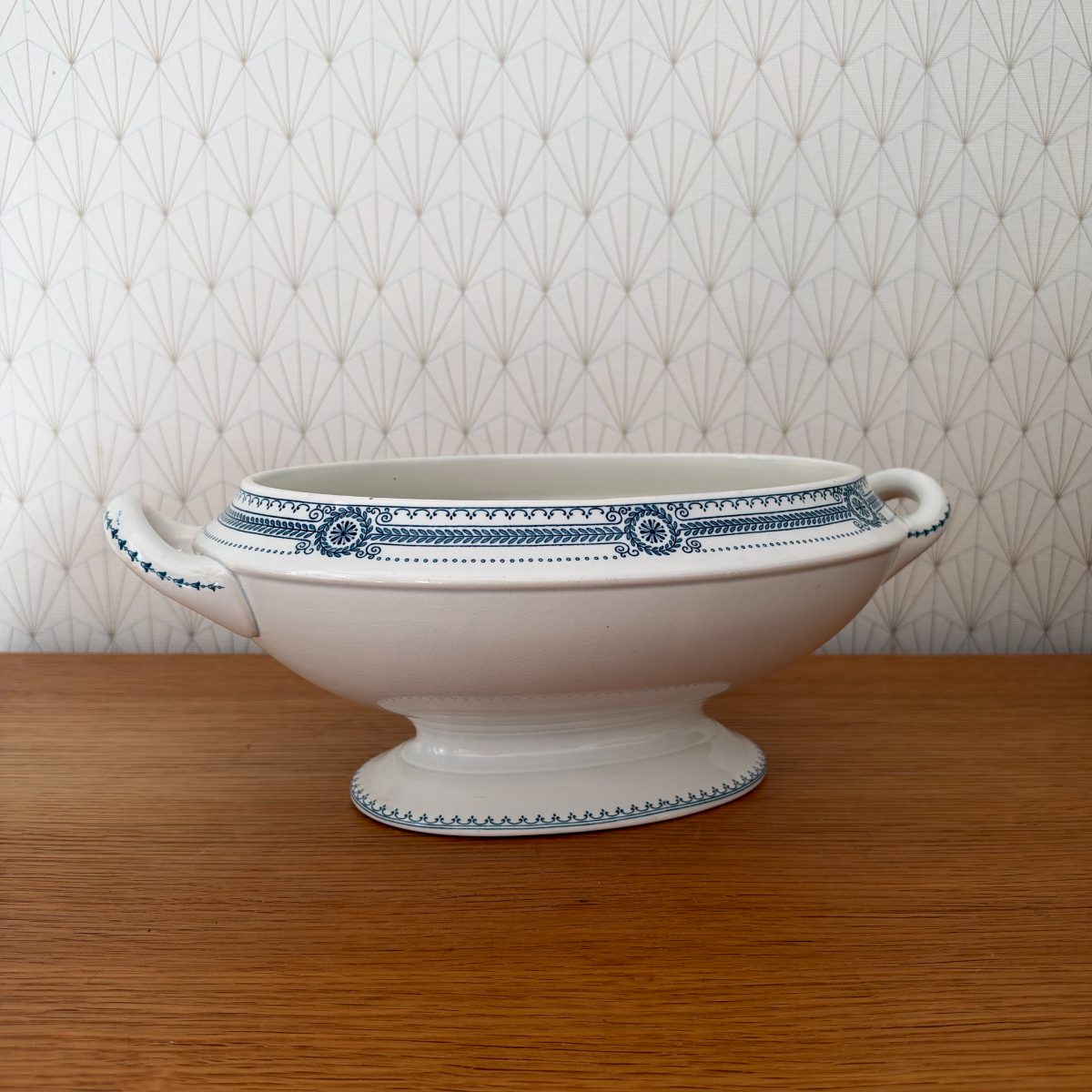 Antique French ironstone tureen base without lid, white with blue neoclassical transferware band, two handles, oval footed form, side view on oak table.