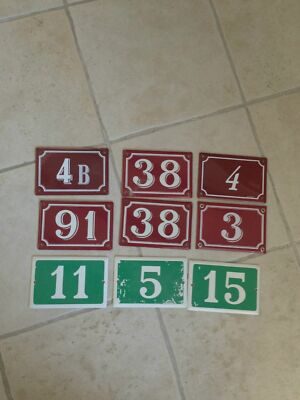 Nine vintage French enamel house number signs in burgundy red and forest green with white numerals, enameled steel, 10x15cm each, showing natural aging from decades of outdoor use.