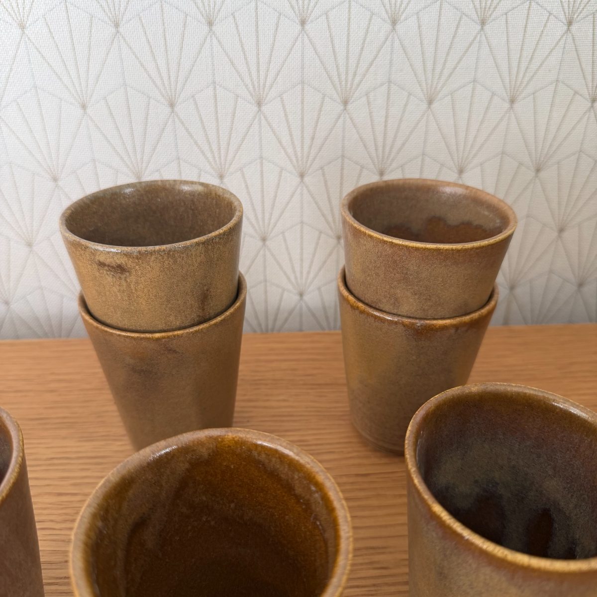 Four French stoneware studio pottery cups stacked in pairs showing matte sandy exterior glaze, two cups open-top in foreground.