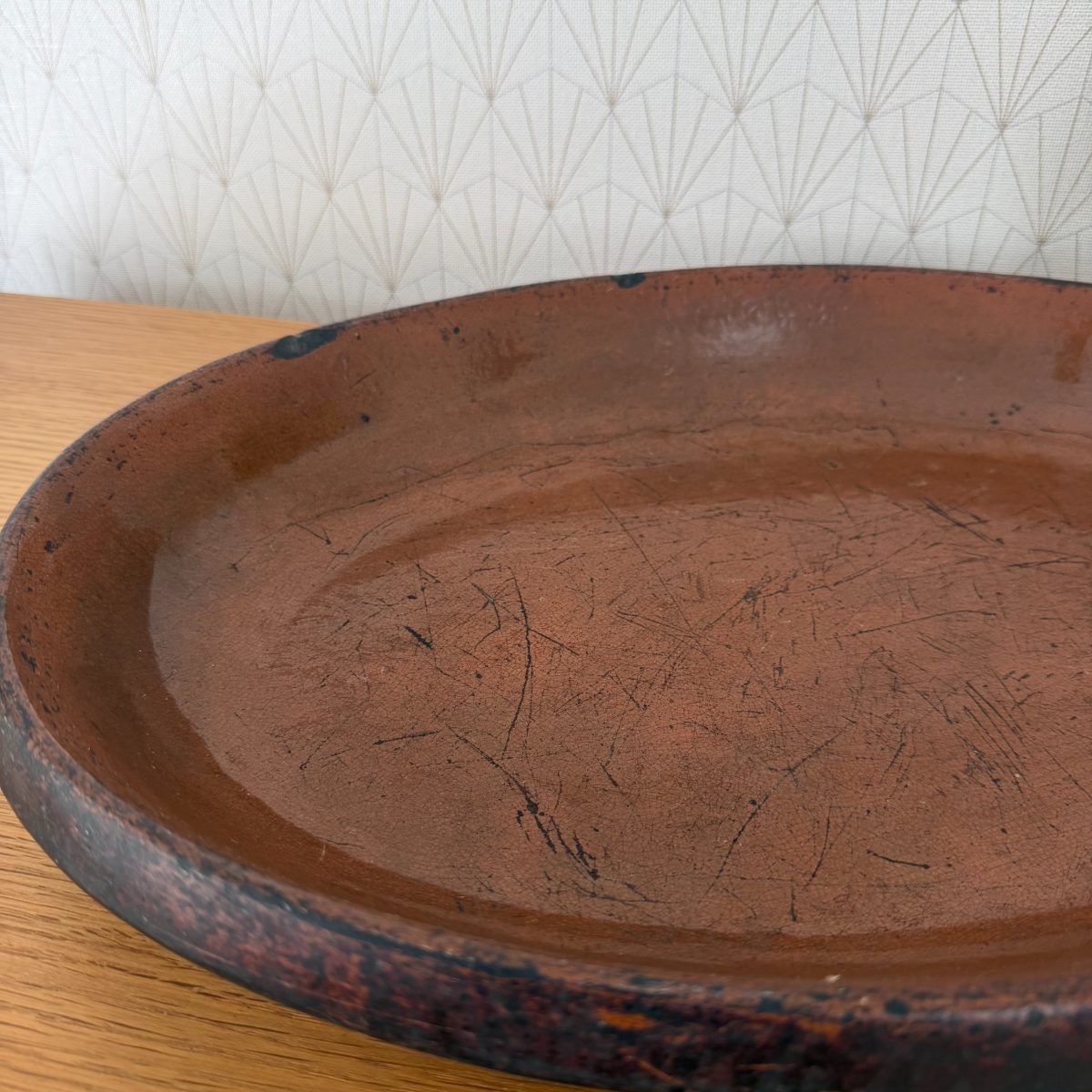 Close-up of the upper left section of the French terracotta dish showing knife scratches and glaze texture on the interior.