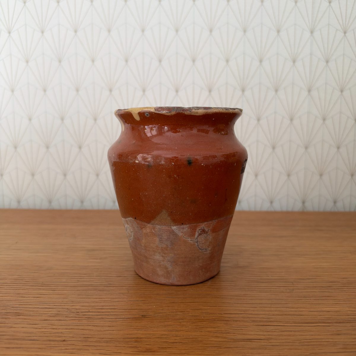 Side view of antique French earthenware pot showing red-brown glaze upper body and unglazed terracotta lower half with age patina and wear.