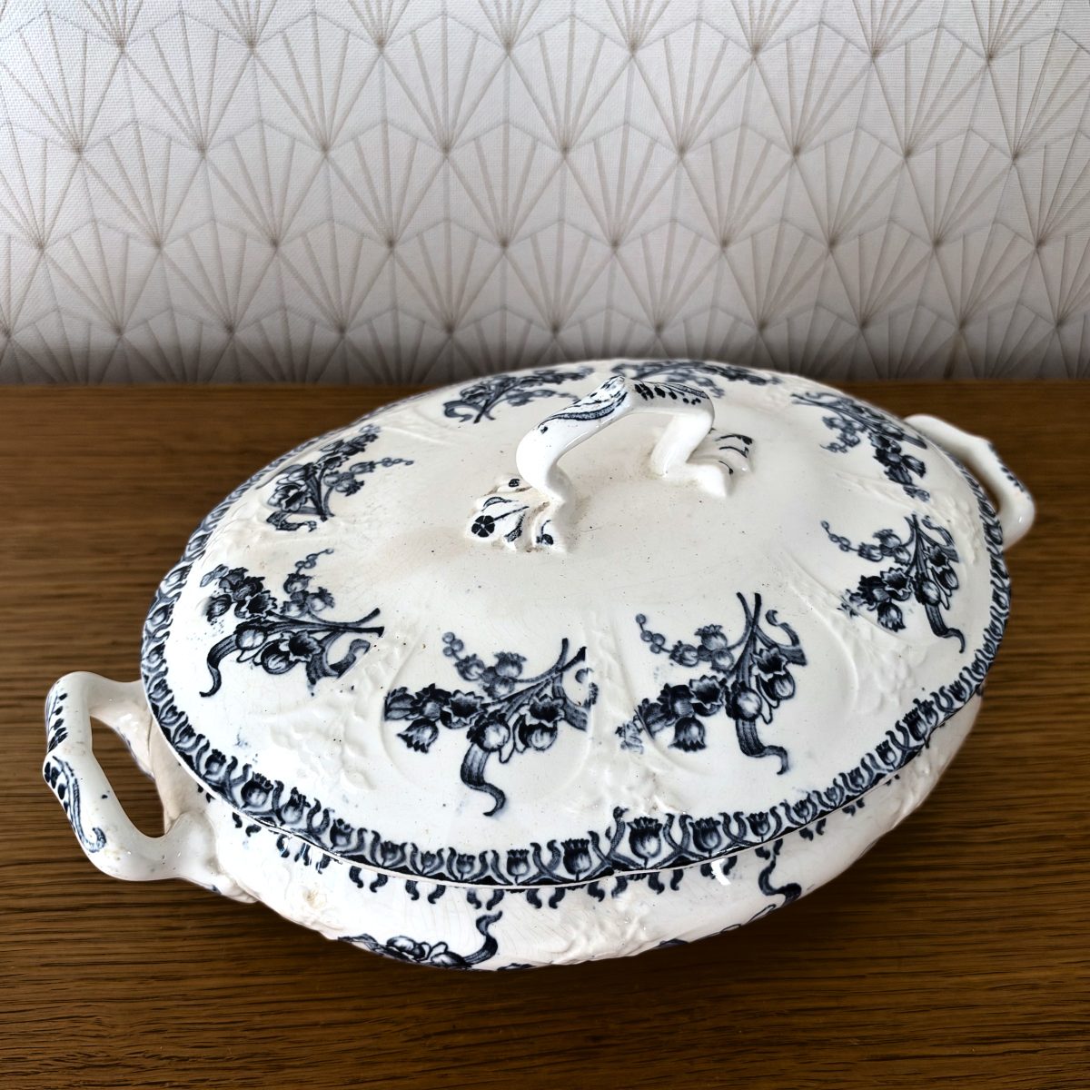 Top-down view of French blue and white transferware tureen lid with ornate floral motifs and decorative handle.