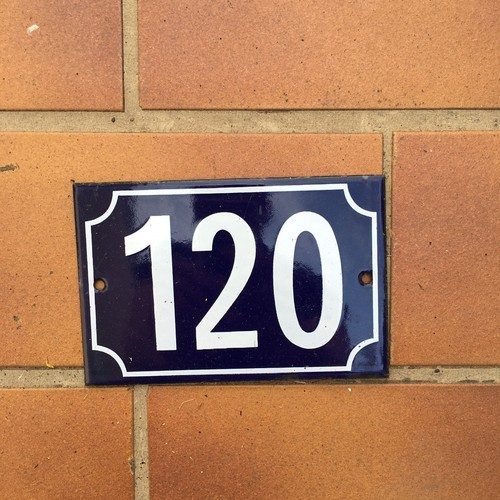 Vintage French enamel house number sign displaying 120 in bold white numerals on deep navy blue enameled steel rectangular plate with curved corners and mounting holes