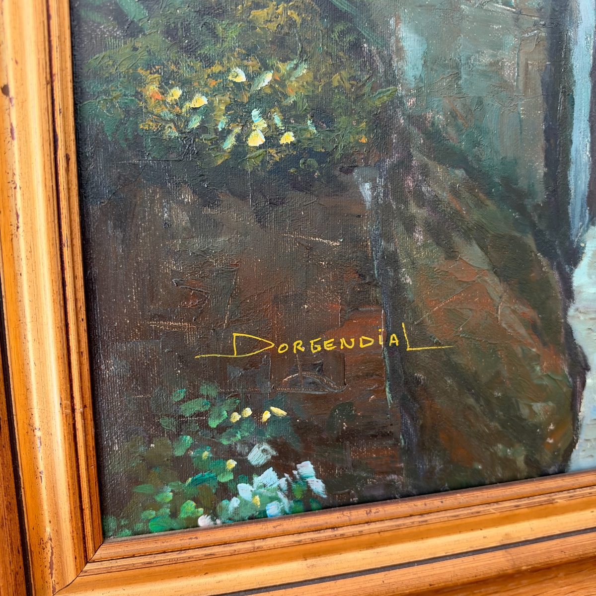 Close-up of lower left corner of French oil painting showing yellow signature Dorgendial in painted letters on dark shadowed foreground with flowers.
